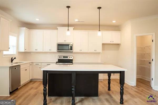 a kitchen with stainless steel appliances granite countertop a sink a stove a refrigerator and white cabinets with wooden floor