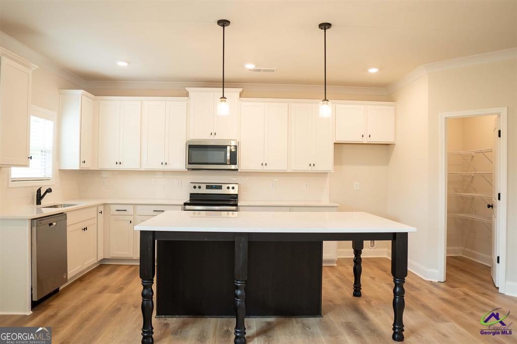 119 Bluecoat Trail Byron, GA 31008 - Photo 29 of 37 a kitchen with stainless steel appliances kitchen island a table chairs sink and cabinets