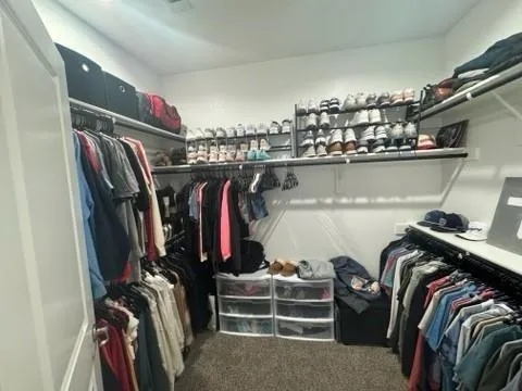 a view of walk in closet with clothes and shoes