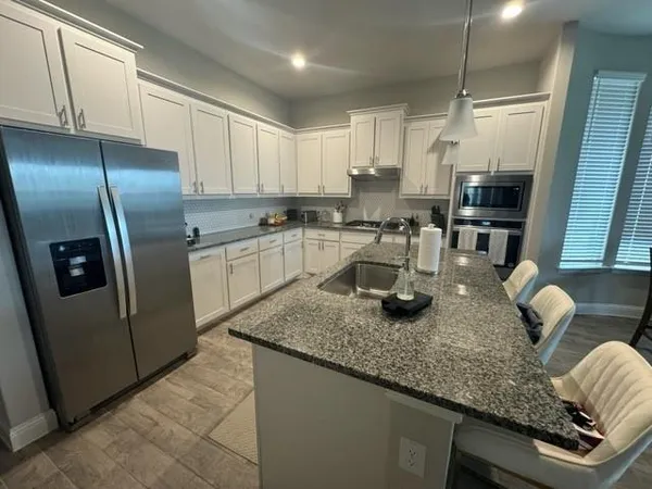 a kitchen with stainless steel appliances granite countertop a sink refrigerator and microwave