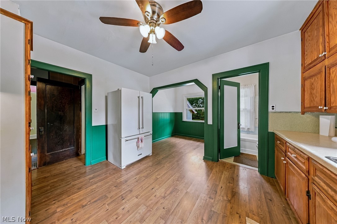 24958 Kennedy Ridge Road North Olmsted, OH 44070 - Photo 14 of 43 Wood-finish flooring throughout, white upper walls with green wainscoting, wood cabinetry, and a ceiling fan with light fixture