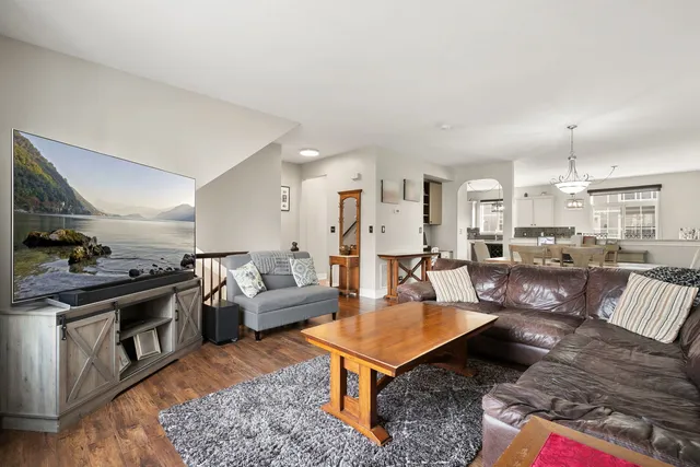 a living room with furniture a rug kitchen view and a chandelier