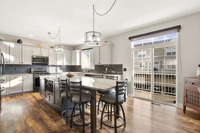 a kitchen with stainless steel appliances granite countertop a stove top oven a refrigerator a sink and white cabinets with wooden floor