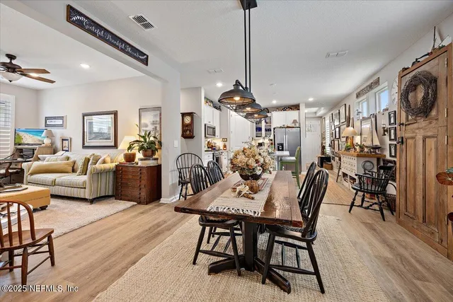a view of a dining room and livingroom with furniture wooden floor a chandelier