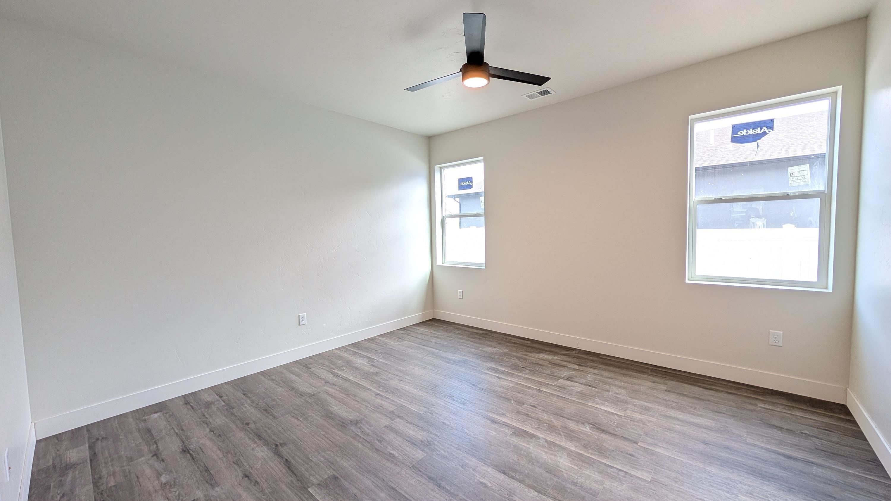 1730 Caliper Way Fruita, CO 81521 - Photo 11 of 15 an empty room with wooden floor chandelier fan and windows