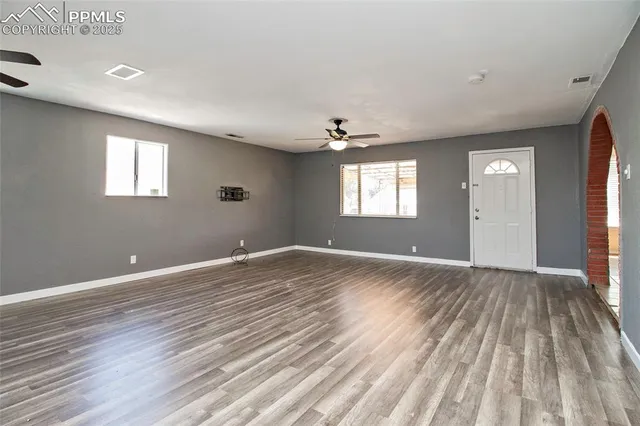 a view of empty room with wooden floor and fan