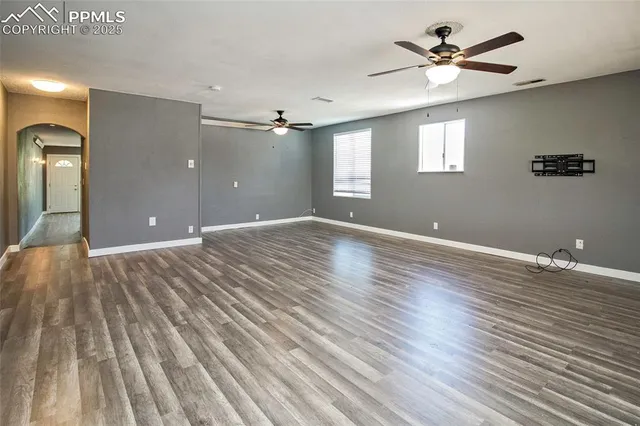 a view of an empty room with window and wooden floor