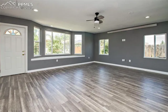 a view of an empty room with wooden floor and a window