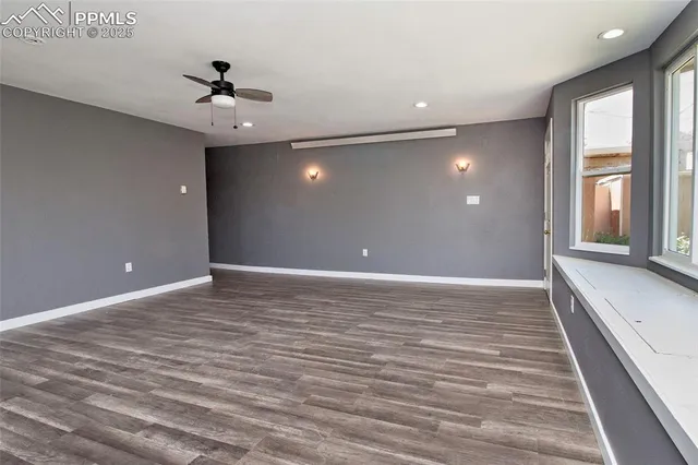 a view of an empty room with a window and wooden floor