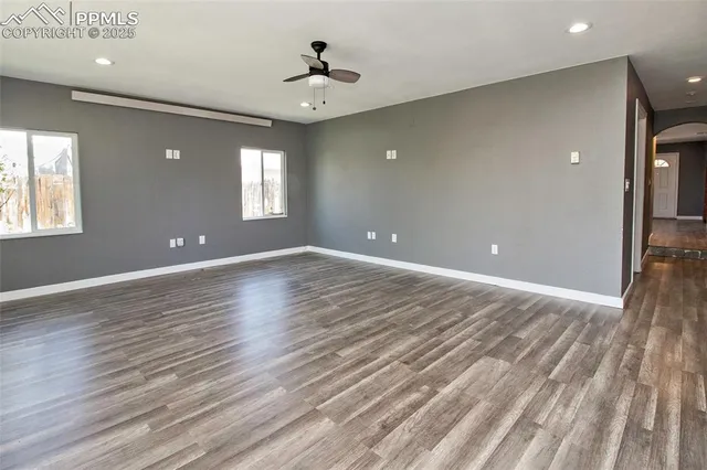 a view of an empty room with window and wooden floor