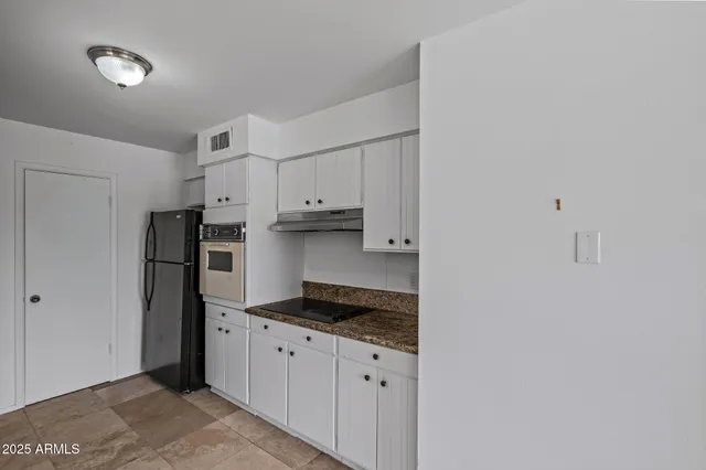 a kitchen with granite countertop a refrigerator and a stove top oven