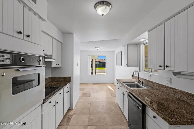 a kitchen with granite countertop a sink stove and cabinets