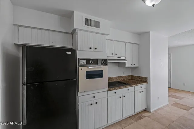 a kitchen with granite countertop white cabinets and refrigerator