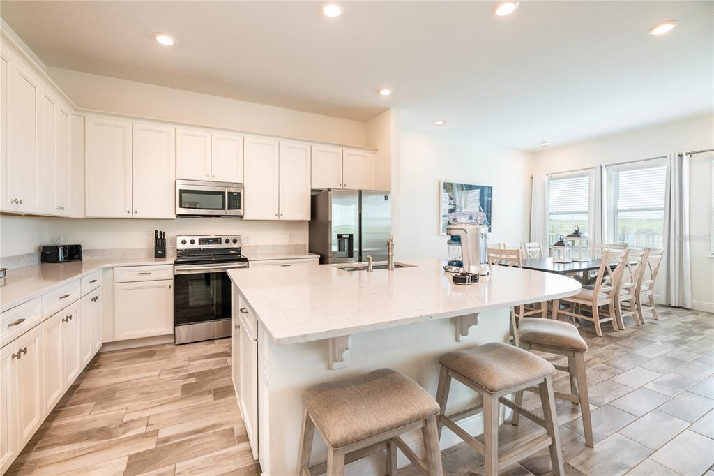 8145 Surf Street Kissimmee, FL 34747 - Photo 6 of 28 a large kitchen with kitchen island white cabinets and stainless steel appliances