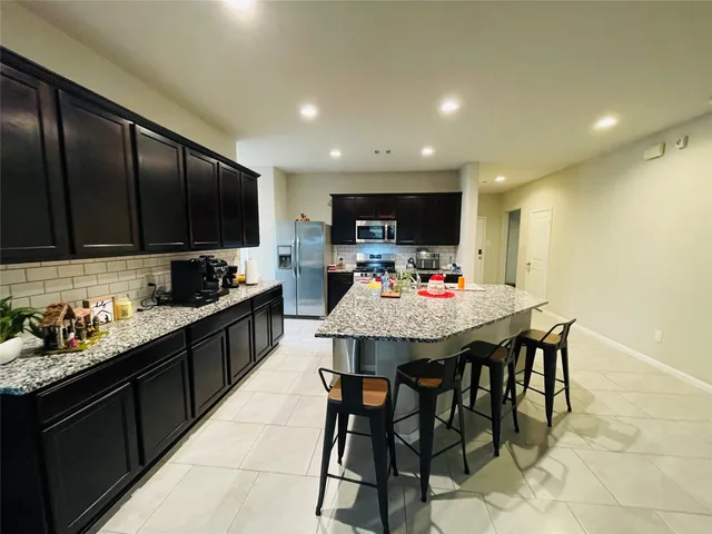 a kitchen with stainless steel appliances kitchen island granite countertop a stove a sink a refrigerator and a refrigerator