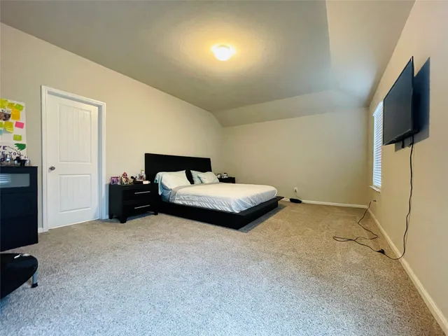 a spacious bedroom with a bed and a flat screen tv