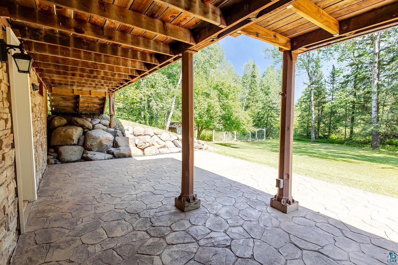 29 Ridge Road Esko, MN 55733 - Photo 34 of 41 Covered patio featuring a stamped concrete surface, exposed wood beam ceiling, and structural wood support posts