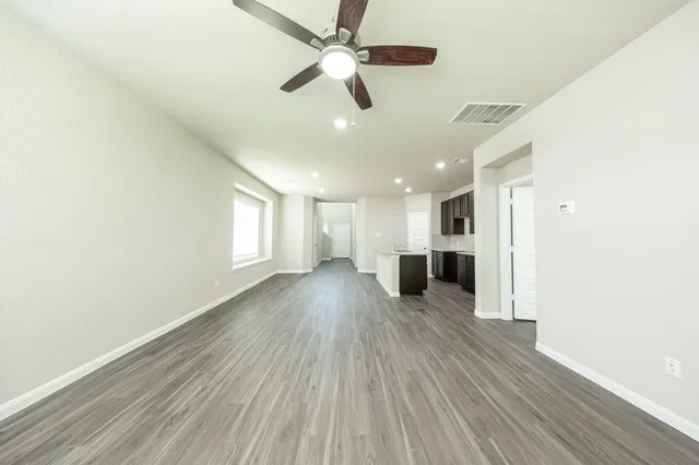 a view of a big room with wooden floor a ceiling fan and windows