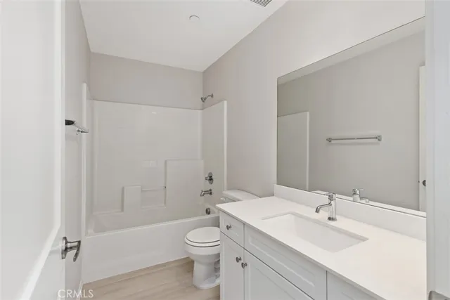 a bathroom with a toilet a sink a mirror a bathtub and vanity