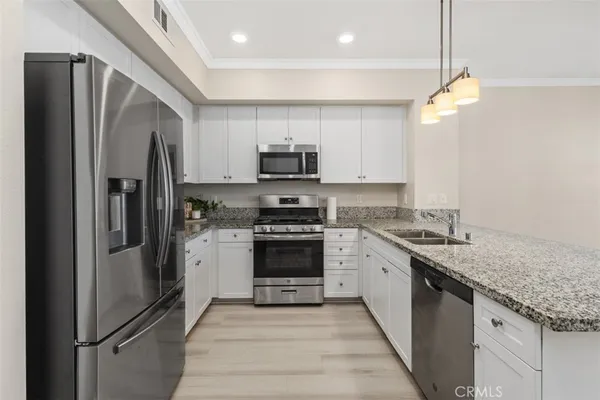 a kitchen with stainless steel appliances granite countertop a refrigerator a stove a sink and a microwave