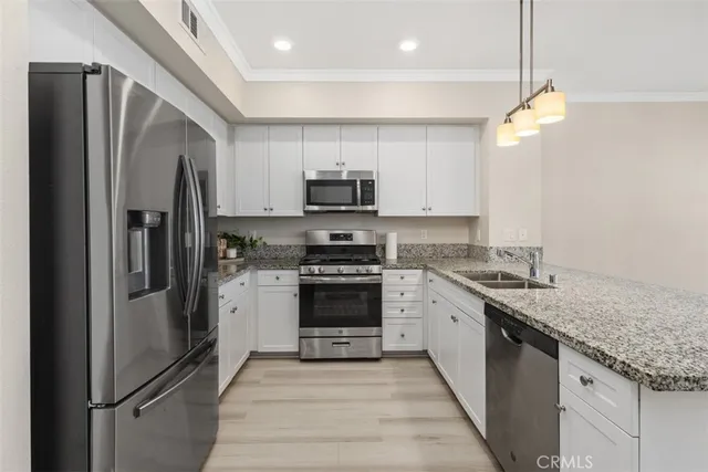 a kitchen with stainless steel appliances granite countertop a refrigerator a stove a sink and a microwave