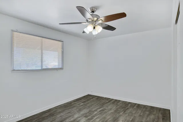 an empty room with wooden floor and ceiling fan
