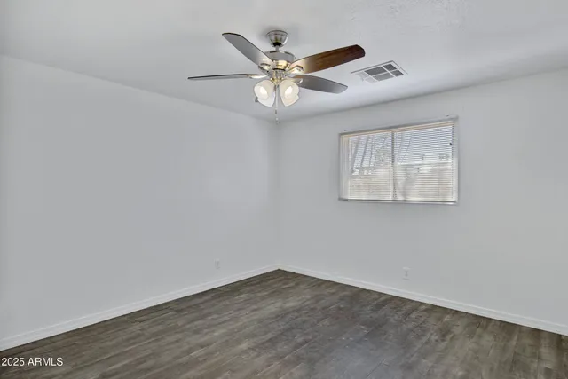 an empty room with wooden floor and ceiling fan