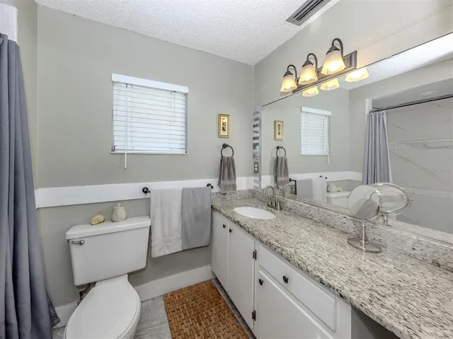 a bathroom with a granite countertop toilet sink and mirror