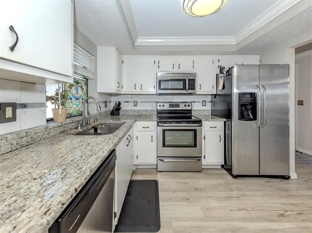 a kitchen with stainless steel appliances granite countertop a stove a sink and a refrigerator