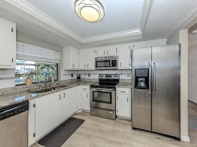 a kitchen with a sink stainless steel appliances and white cabinets
