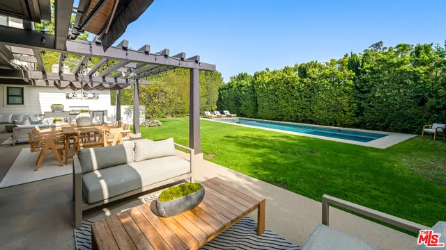a view of a patio with couches table and chairs with wooden floor and fence