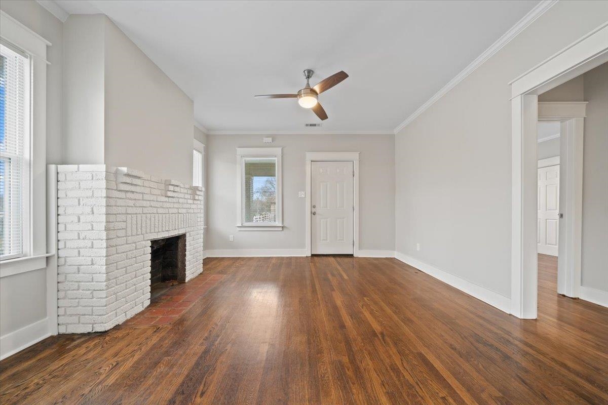 598 Spring Street Memphis, TN 38112 - Photo 4 of 29 an empty room with wooden floor fireplace and windows