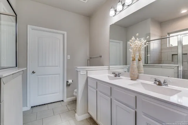 a spacious bathroom with a double vanity sink a mirror and a shower