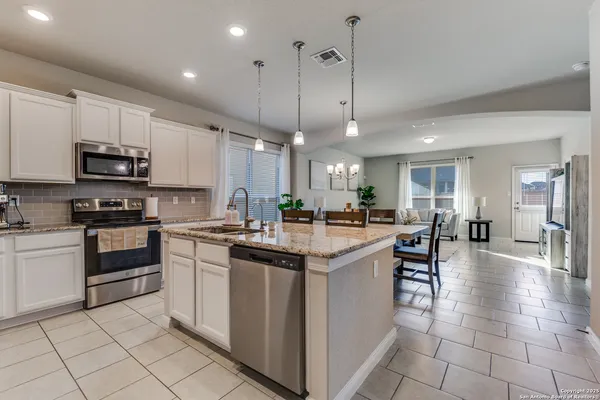 a kitchen with kitchen island granite countertop a sink counter top space appliances and cabinets