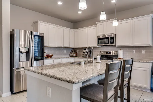 a kitchen with kitchen island granite countertop a refrigerator and a stove top oven