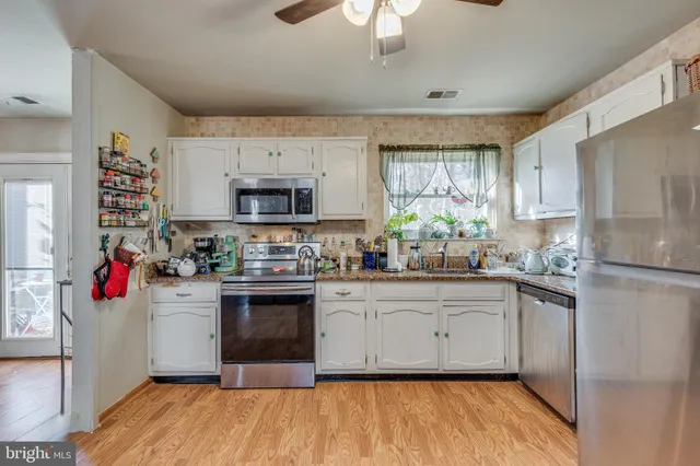 a kitchen with stainless steel appliances a white cabinets and a stove top oven