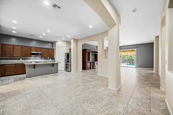 a view of an empty room with a flat screen tv with kitchen view