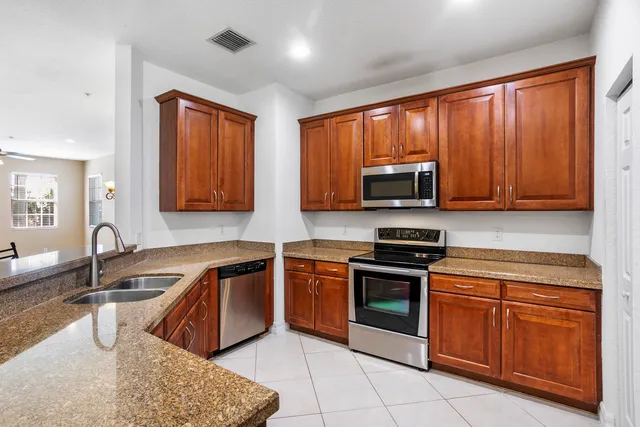 a kitchen with stainless steel appliances granite countertop wooden cabinets a stove top oven a sink and dishwasher