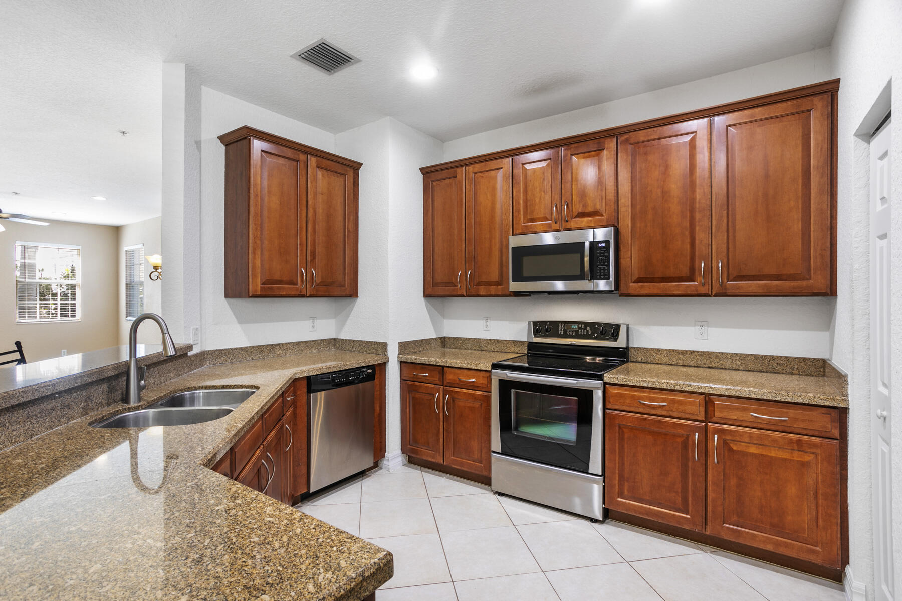 114 Locustberry Lane, Unit 101 Jupiter, FL 33458 - Photo 2 of 59 a kitchen with stainless steel appliances granite countertop wooden cabinets a stove top oven a sink and dishwasher