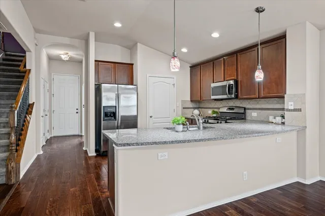 a kitchen with kitchen island granite countertop a sink cabinets and stainless steel appliances
