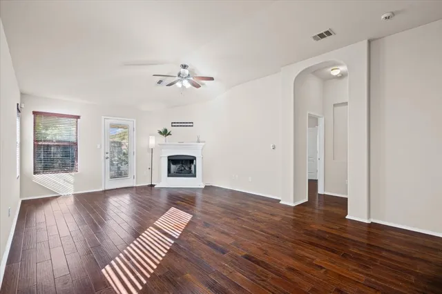 a view of an empty room with wooden floor and a fireplace