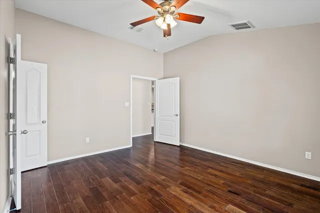 an empty room with wooden floor fan and windows