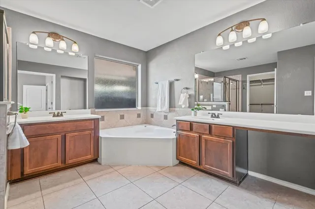 a spacious bathroom with a double vanity sink a mirror a bathtub and a window