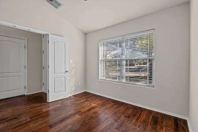 a view of an empty room with wooden floor and a window