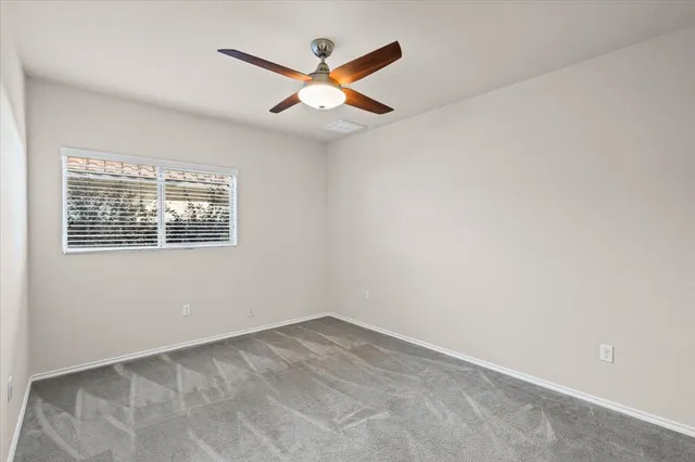 an empty room with a window and a fan