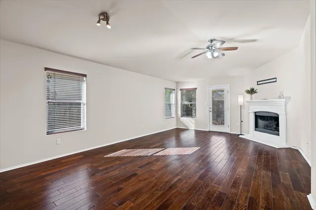 a view of an empty room with wooden floor fireplace and a window