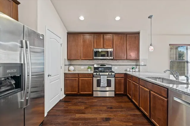 a kitchen with stainless steel appliances granite countertop a sink a stove a refrigerator and cabinets