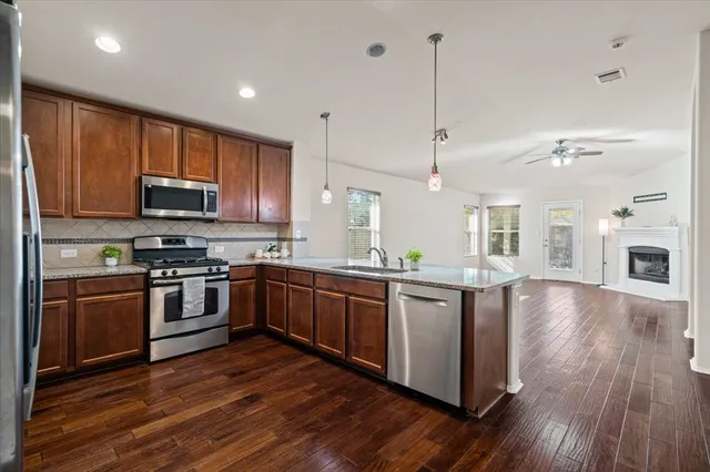 a kitchen with stainless steel appliances granite countertop wooden floors and granite counter tops