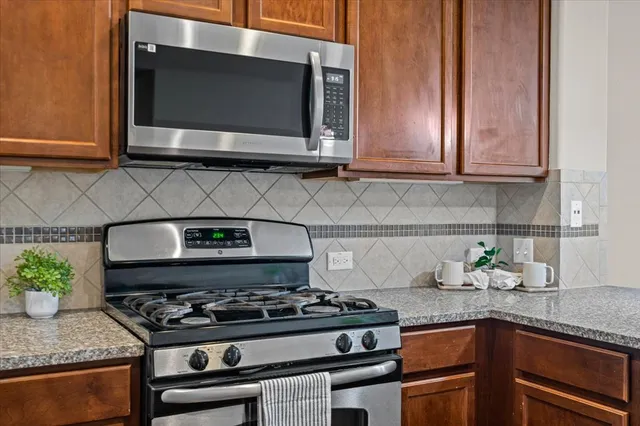 a kitchen with granite countertop stainless steel appliances a stove a microwave and cabinets