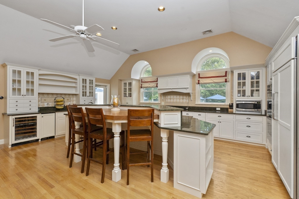 6 Heron Way Mashpee, MA 02649 - Photo 12 of 42 a kitchen with stainless steel appliances kitchen island granite countertop a stove top oven a sink a dining table and chairs with wooden floor